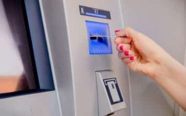 Woman's hand inserting Credit Card Debt Visa into the ATM