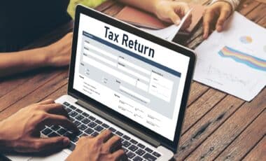 A person filing out a tax return form on a laptop