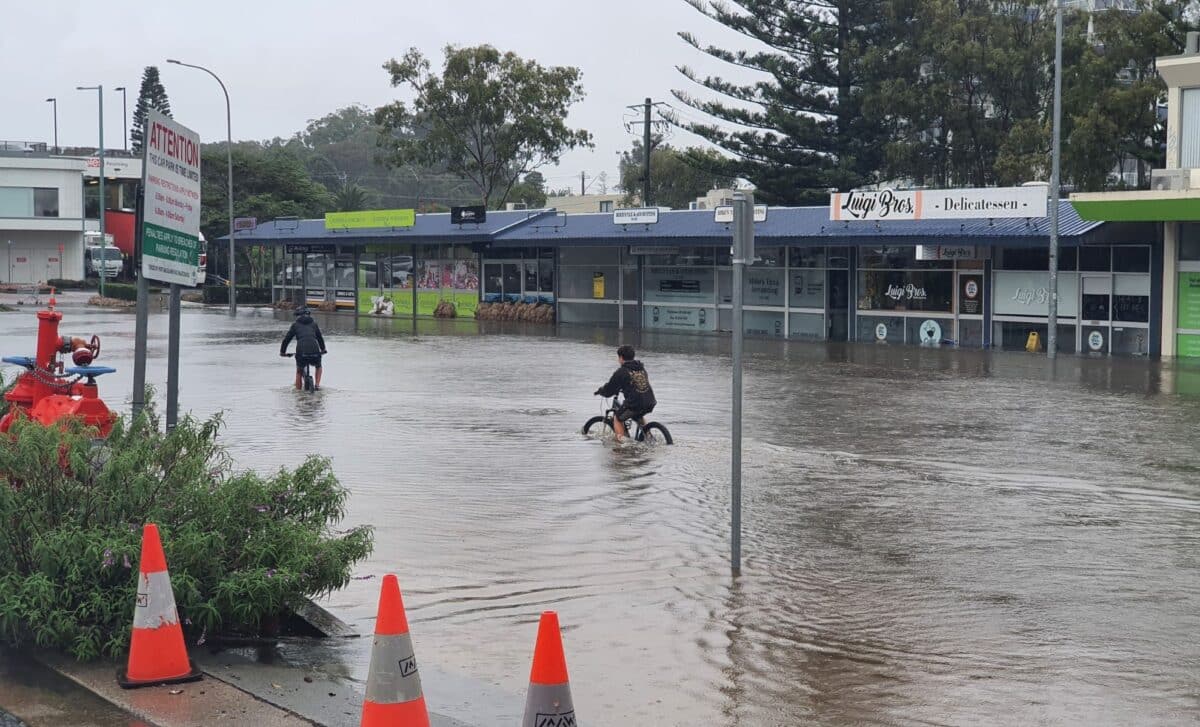 Two persons riding bikes in a flooded street