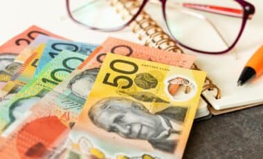 Australian bank notes, a pen, and a pair of glasses