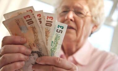 An Old State Pensioner Holding A Handful Of British Bank Notes.