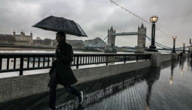 Christmas-person walking along a riverside promenade near Tower Bridge in London