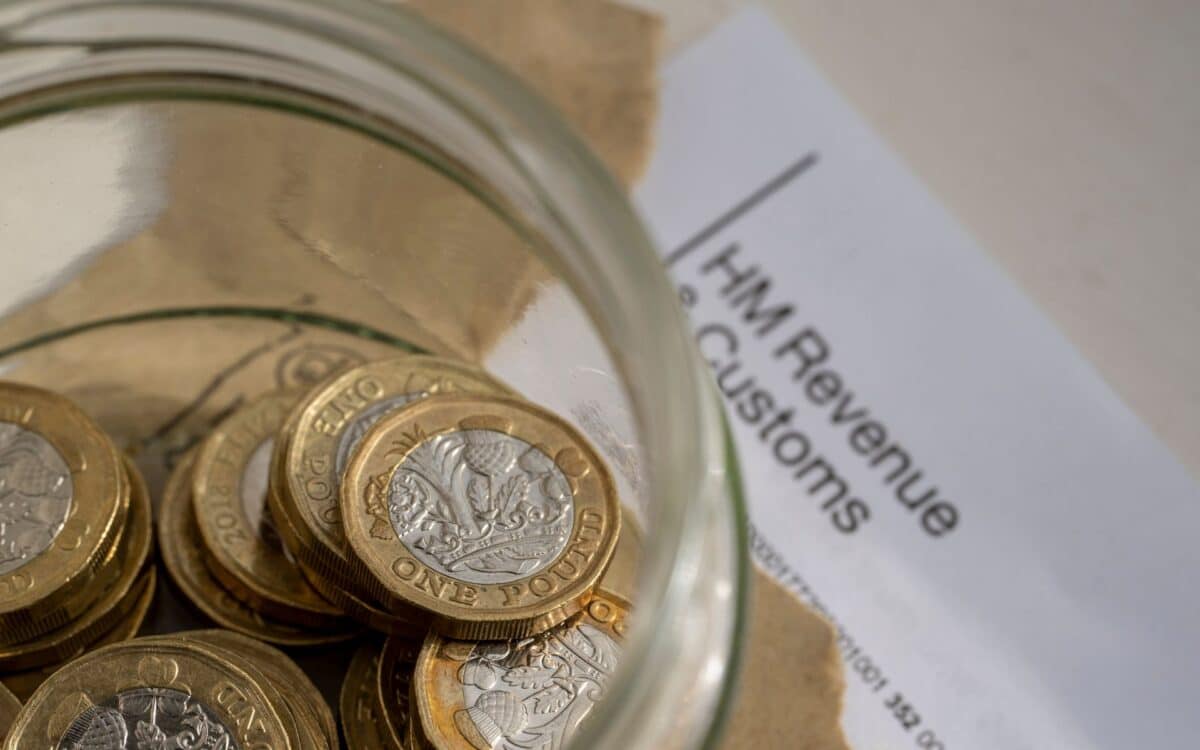 Inheritance Tax-Jar filled with one-pound coins alongside a document from HM Revenue & Customs (HMRC)