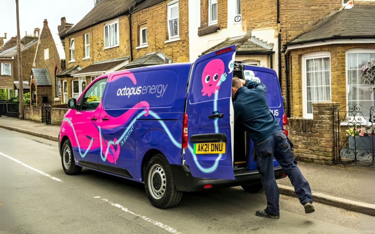 An Octopus Energy van is parked on a residential street with a worker unloading items.