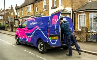 An Octopus Energy van is parked on a residential street with a worker unloading items.