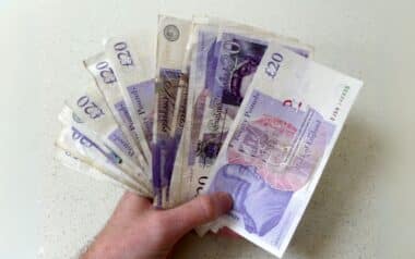 a hand holding multiple £20 British banknotes