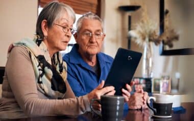 An elderly couple is intently looking at a Pension savings on the tablette