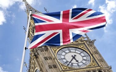 British-the Union Jack, the national flag of the United Kingdom, flying prominently in the foreground. In the background, the Elizabeth Tower