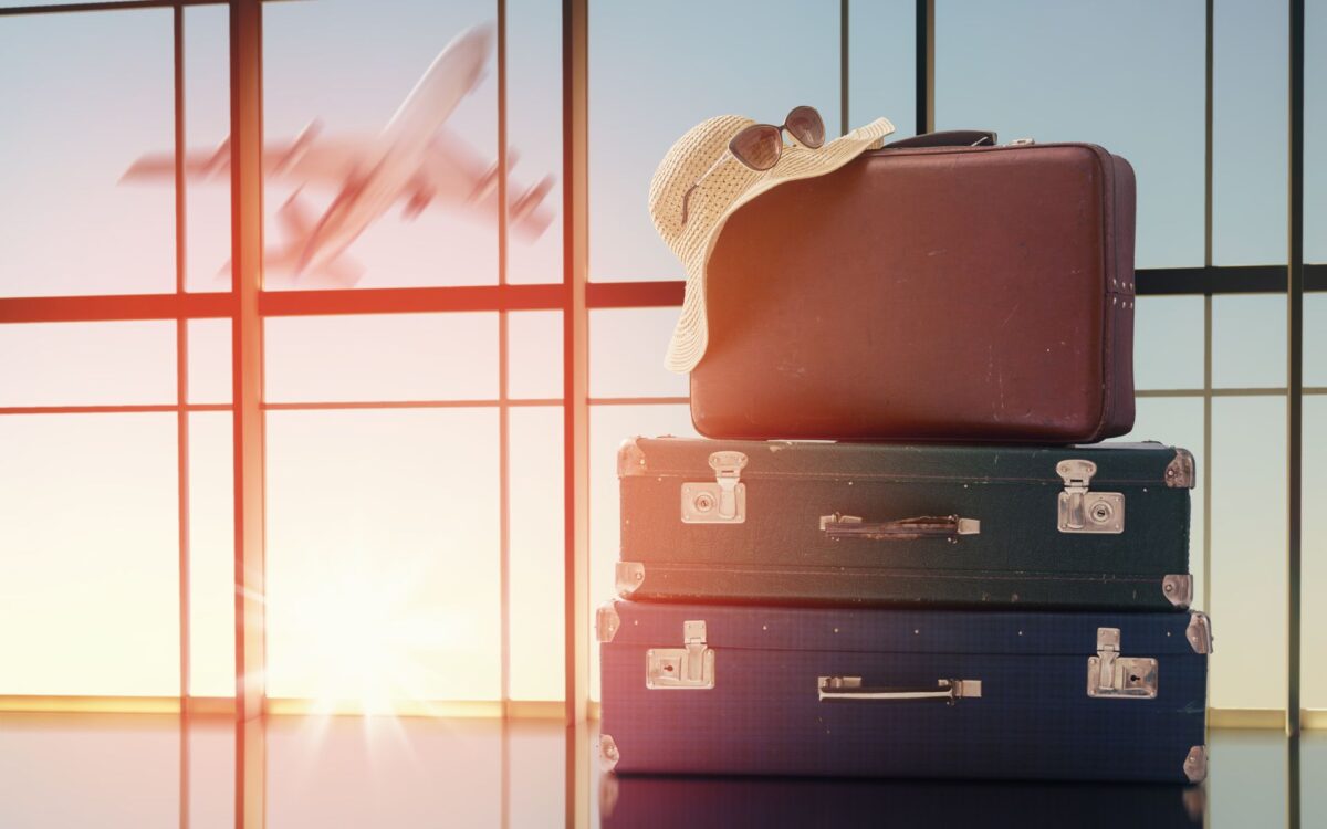 DWP-Three suitcases placed near a large window in an airport terminal