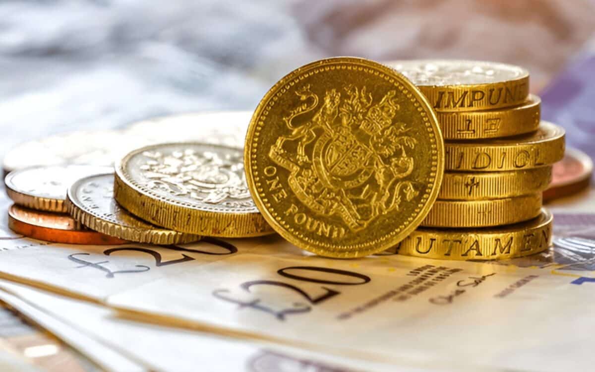 London-close-up of British currency, including stacks of gold-coloured one-pound coins and scattered £20 notes.