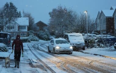 Met Office-Houses with white-topped roofs and snowy gardens line the street, while vehicles are parked on either side, their exteriors blanketed in snow