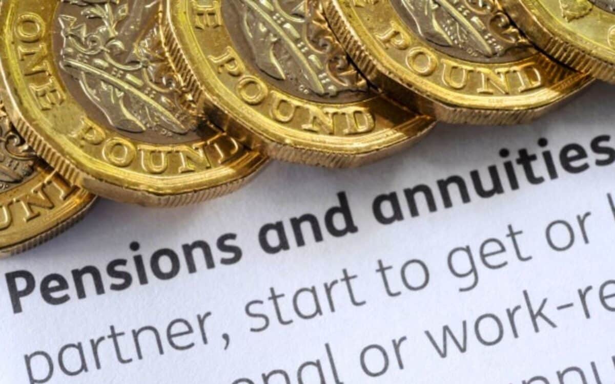 Pensioners-close-up view of several British one-pound coins stacked on top of a document. The document contains text related to Pensions and annuities.