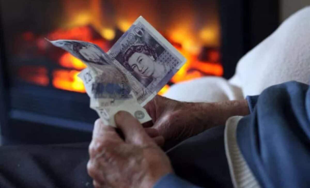 Person Holding UK Banknotes with a Fireplace in the Background in Reference to the Cold Weather Payments