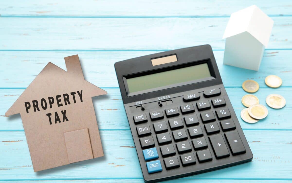 Property tax text on brown paper house model with dollar ban