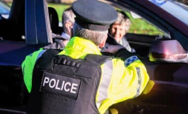 A PSNI officer talks to an elderly driver as he stops traffic to perform a random driver check