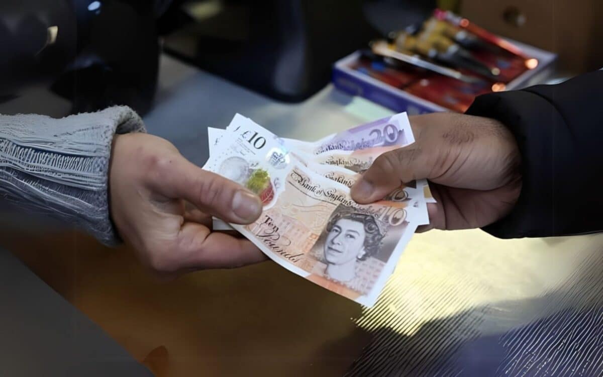 A person handing over £10 and £20 banknotes, likely as part of a transaction