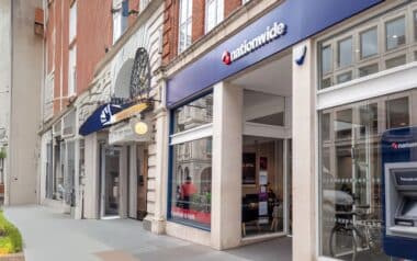 A Nationwide branch on a British high street, featuring a modern glass frontage and an ATM outside the building.