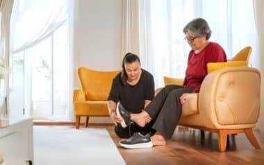 A woman helping an elderly person put on a pair of shoes