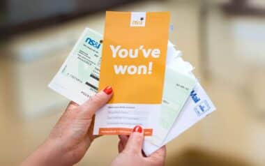 A hand holding a "You've won!" letter from NS&I with Premium Bonds prize warrants