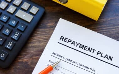 A repayment plan document with a pen and calculator