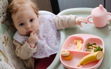 Cute baby girl tries to eat her first meal