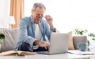 Mature man squinting using laptop, looking at pc screen