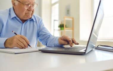 Senior Man Using Laptop and Taking Notes