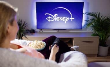 Woman holding TV remote watching Disney +