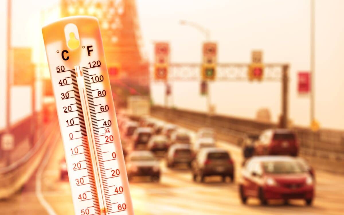 Thermometer in front of cars and traffic during heatwave