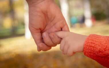 Parent and Child Holding Hands in Autumn Park