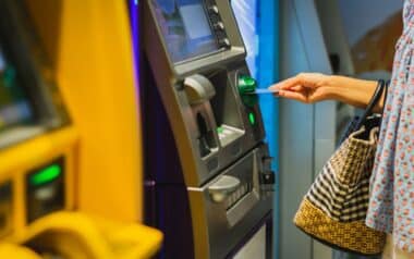 Woman hand insert a credit card into an ATM machine.