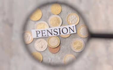 Word PENSION with Coins Visible through Magnifier, Closeup. Concept of Pension