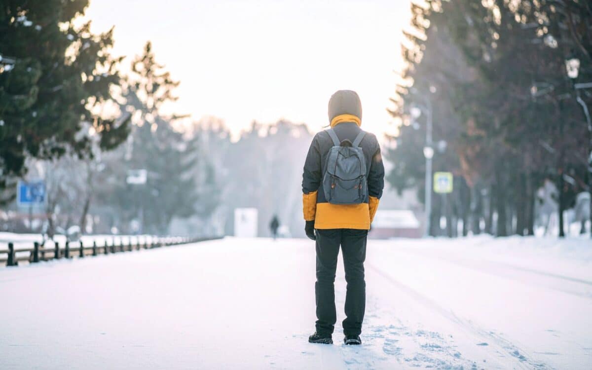 Person with Backpack on Snowy Road in Winter