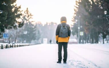 Person with Backpack on Snowy Road in Winter