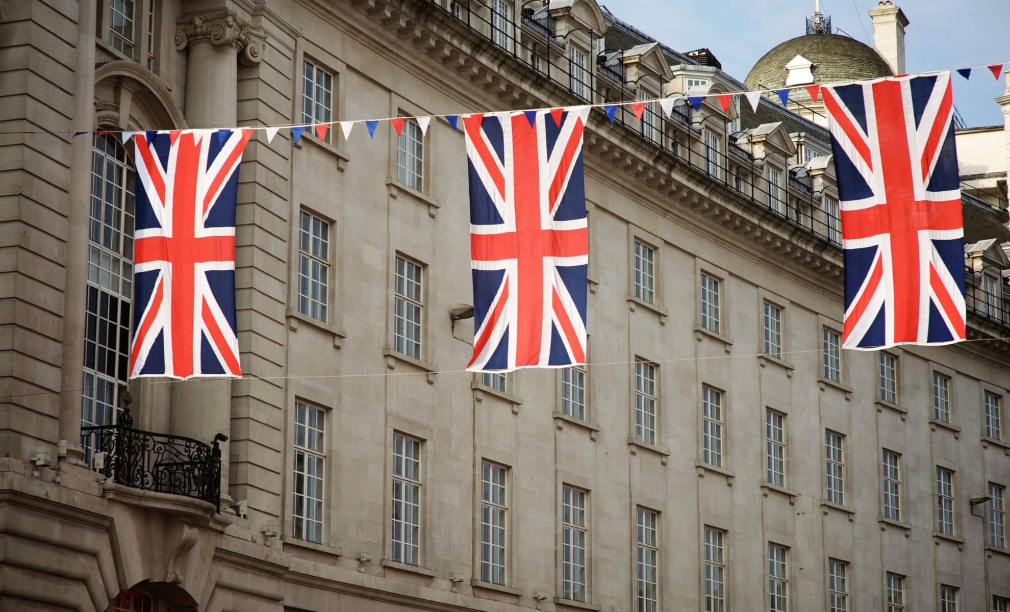Union Jack Flags Strung In Front Of A Building to refer to UK Could See Extra Bank Holiday in 2025 with Plans for a Four-Day Weekend