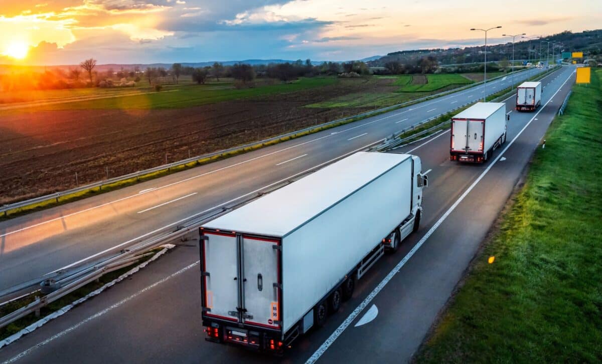 Transport trucks with trailers traveling on a paved highway
