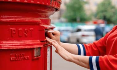 Woman putting letter in a red mail box
