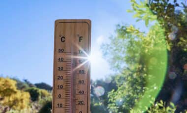 Outdoor thermometer showing a high temperature under blazing sunshine.