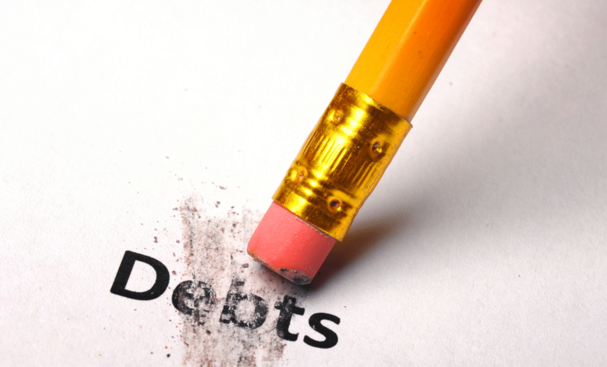 The Word "Debts" Being erased From a White Sheet of Paper With a Pencil Eraser