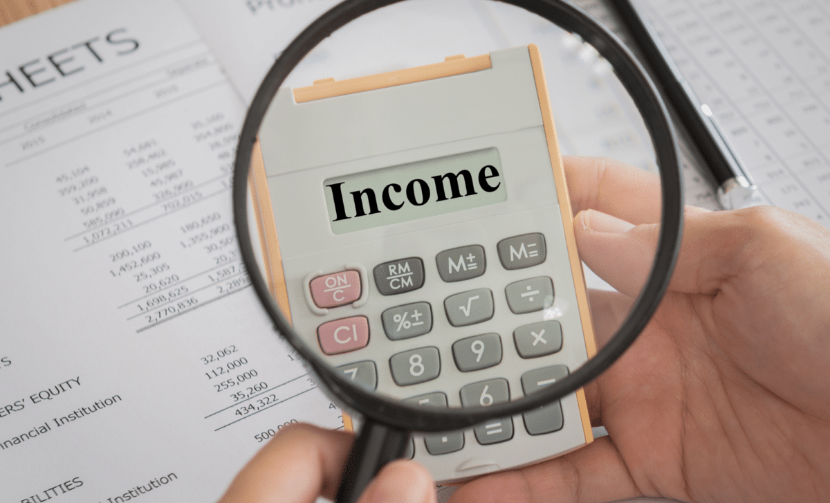 Magnifying Glass Zooming on a Calculator Screen where the Word 'Income' is Written