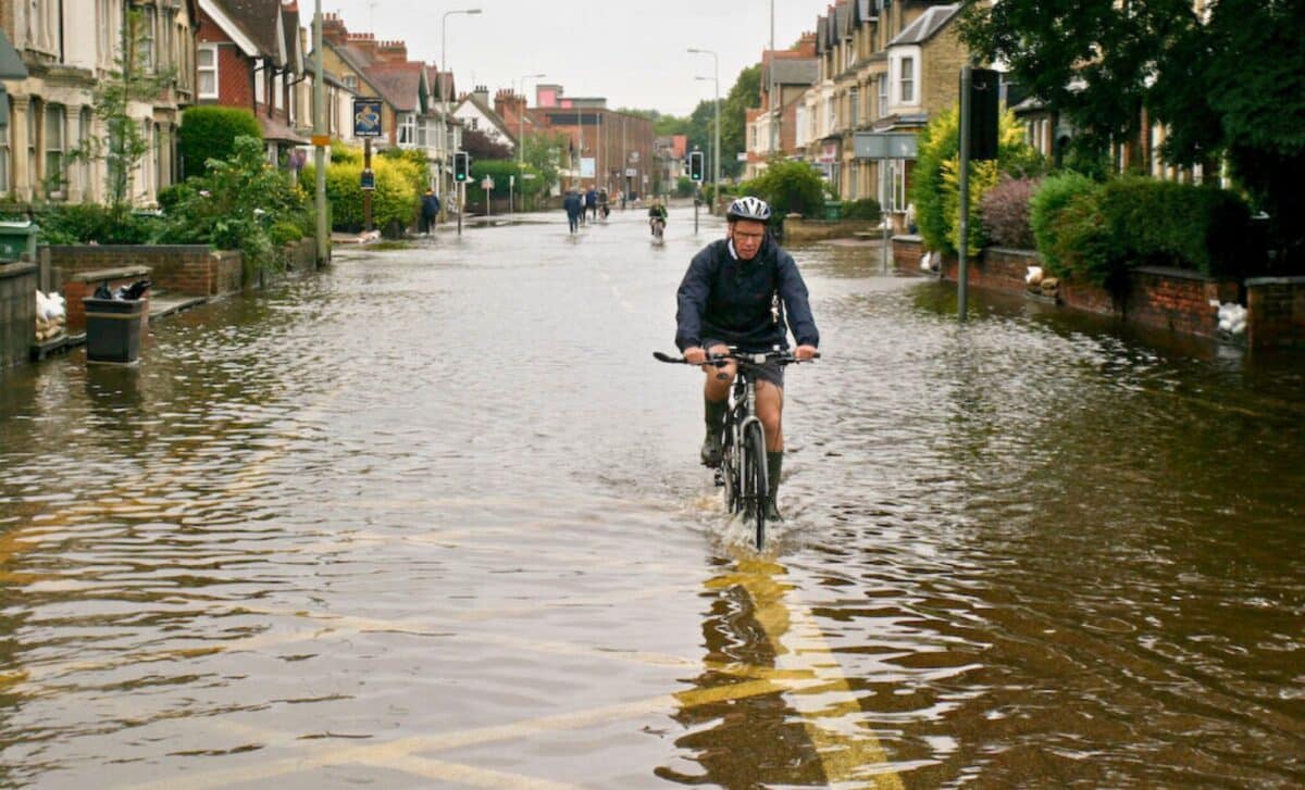 A Man Riding A Bicycle Through A Flooded Street And Rainy Weather