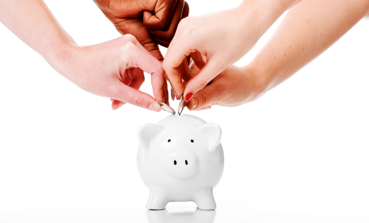 Four Hands Putting Coins In A Piggy Bank Symbolizing Uk Pension Savers