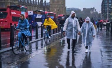 Pedestrians And Cyclists In A Wet Street On A Rainy Day By Westminster Bridge