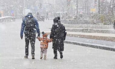 A Couple Holding Their Young Child During Snowy Weather