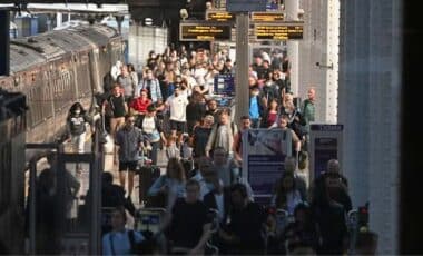 People Walking Through A Railway Station.