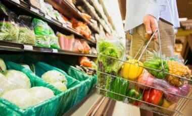 A Man Holding A Grocery Basket Full Of Provisions.