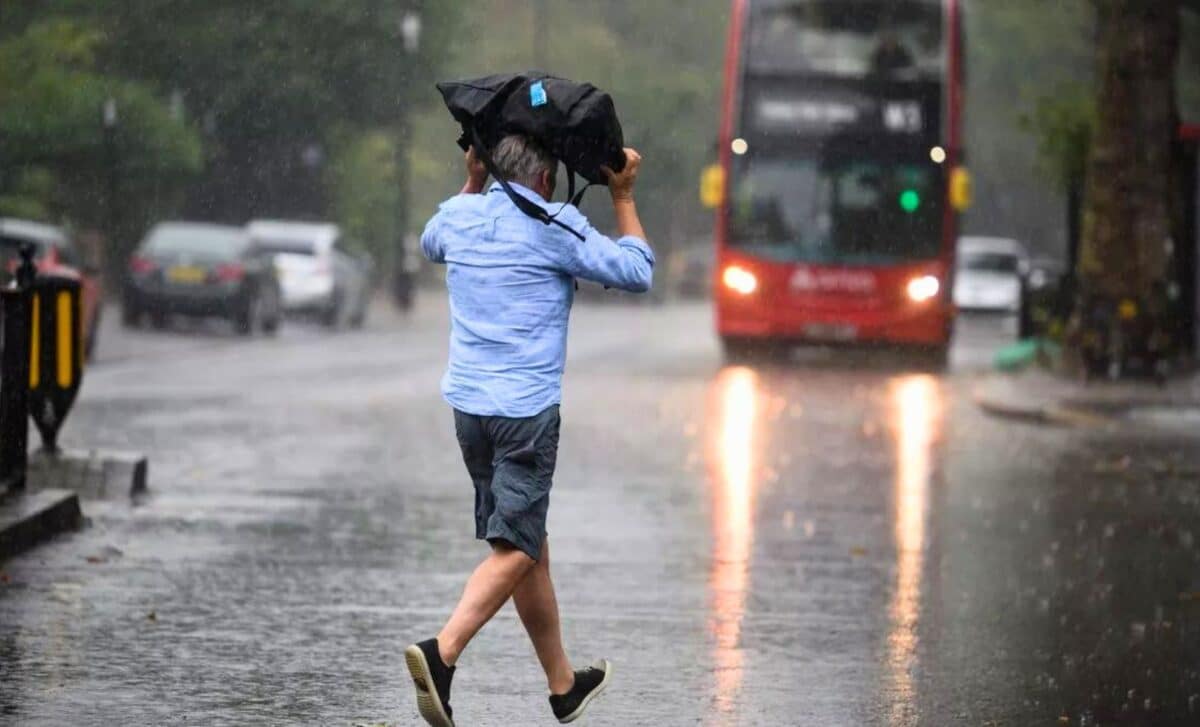 Weather : A Man Running In The Rain, With His Head Covered By A Backpack.