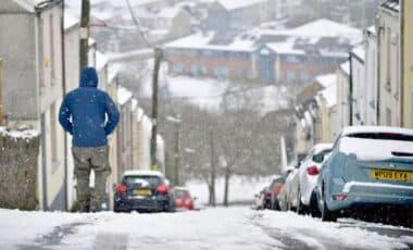 UK Weather : A Person Walking In A Snowy Street Surrounded By Vehicles