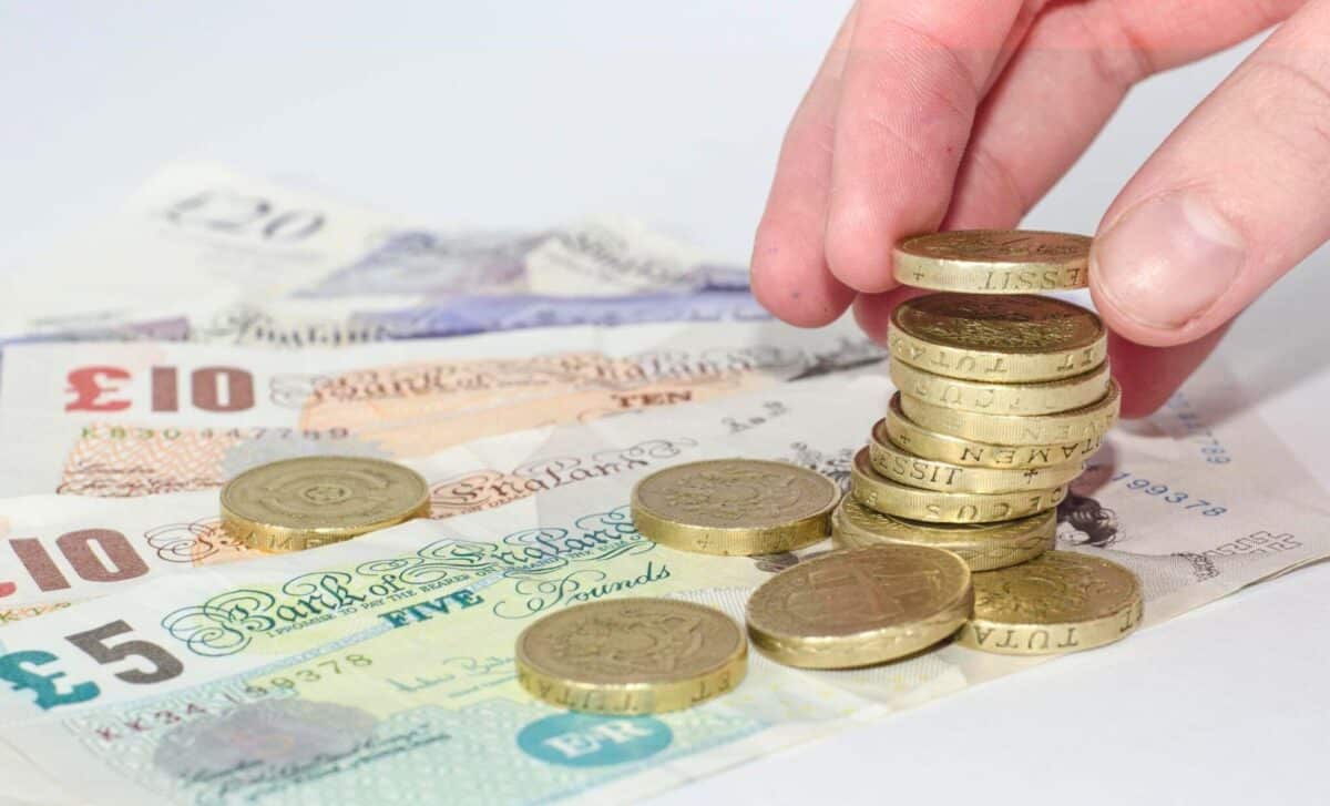 A Person's Hand Takes A British Pound Coin