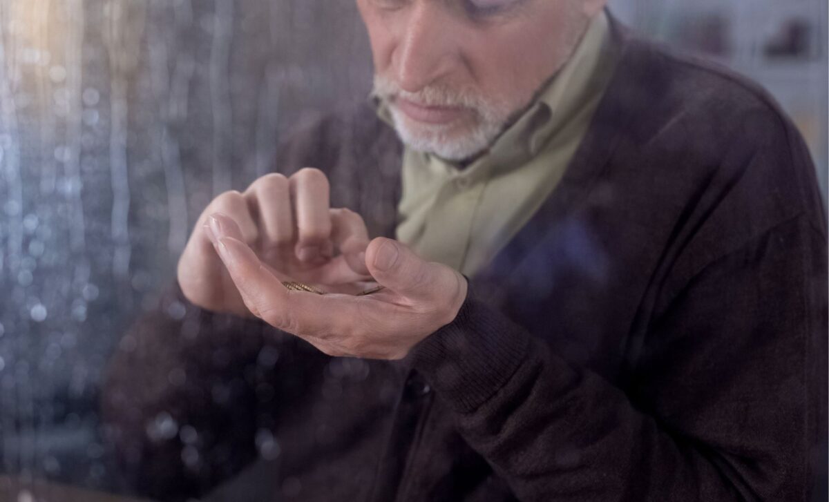 UK Pensioners - An Unhappy Pensioner Counting Coins In His Hand